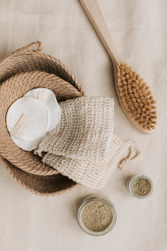 hemp washcloth and cotton pads in braided jute basket beside wooden brush
